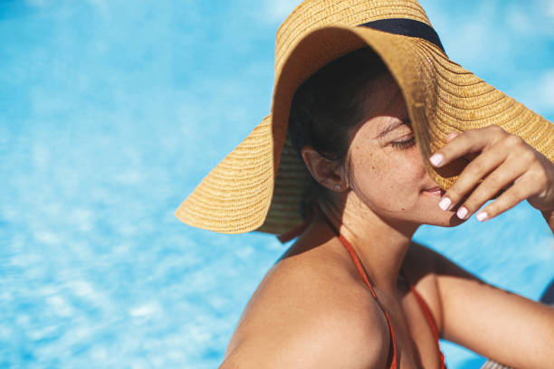 Enjoying summer vacation.Portrait beautiful calm woman in hat relaxing in pool. Holidays and Travel stock photo