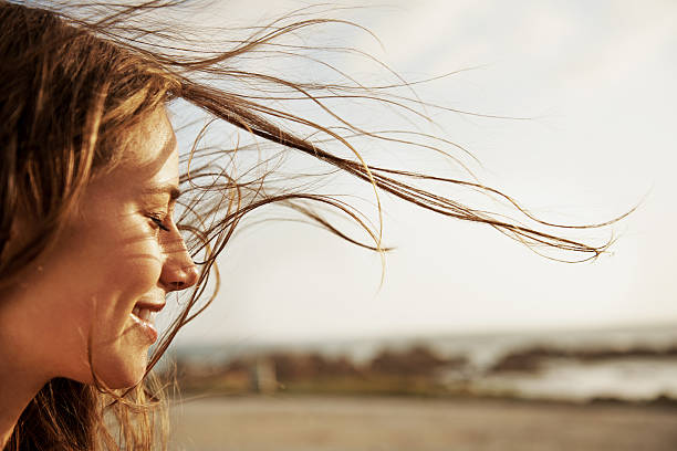 Enjoying the fresh sea air Cropped view of a young woman with the wind in her hair mood stock pictures, royalty-free photos & images