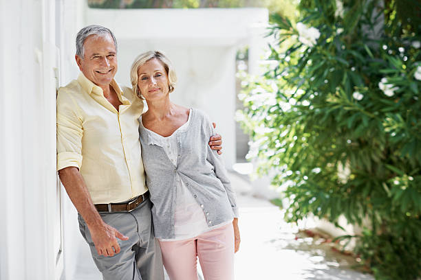 Enjoying the sunshine from our garden Portrait of an older couple posing for the camera in front of their house with copy space 55 59 years stock pictures, royalty-free photos & images