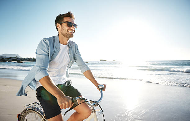 Enjoying the therapeutic feelings of the sea Cropped shot of a young man cycling on the beachhttp://195.154.178.81/DATA/i_collage/pu/shoots/805645.jpg young men stock pictures, royalty-free photos & images
