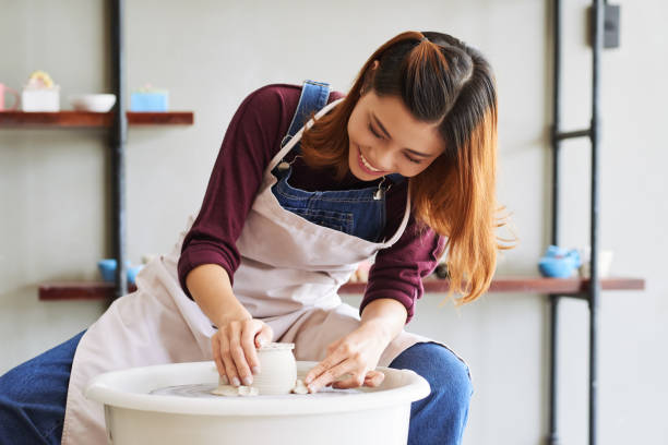 Enjoying workshop Cheerful talented Vietnamese woman enjoying pottery process pottery stock pictures, royalty-free photos & images