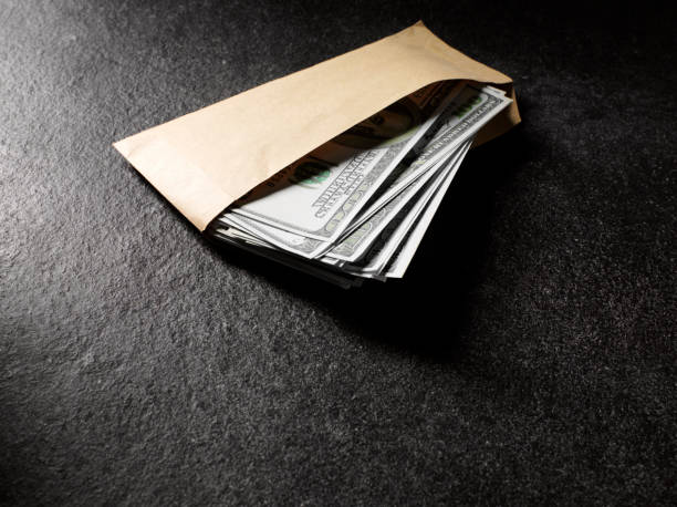 Envelope Full of American Dollars "American dollars in a envelope, with copy space on a slate background.Click on the link below to see more of my business and legal images" bribing stock pictures, royalty-free photos & images