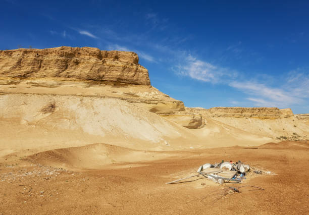 Environmental problem, garbage installation at the bottom of a sand career, Baikonur, Kazakhstan Scenic cliff against the blue sky and a handful of industrial garbage in the foreground baikonur stock pictures, royalty-free photos & images
