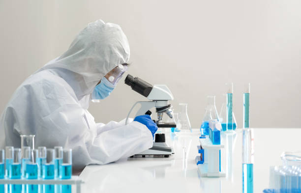 Epidemiological researcher in virus protective clothing use microscopes to look at blood samples of infected people. Coronavirus disease 2019, Omicron strain testing process in  laboratory. stock photo