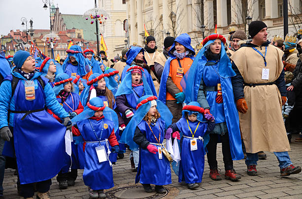 "Warsaw, Poland - January 6th, 2013: Procession during theEpiphany on Krakowskie Przedmieacie. Group og girls in blue costumes, accompanied by women in similar costumes and a man (on the right). Old Town architecture in the background. Horizontal image"
