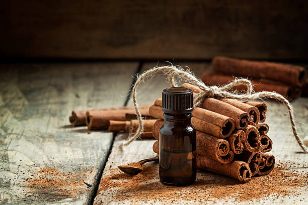 Essential cinnamon oil in a small bottle Essential cinnamon oil in a small bottle, ground cinnamon and cinnamon sticks on old wooden background, selective focus cinnamon stock pictures, royalty-free photos & images