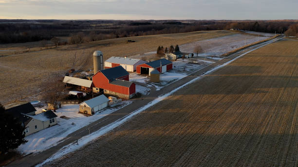Establishing shot of Midwestern countryside in winter.  Aerial view of  rustic road, farm houses, farms along the street. Agricultural field  covered in first snow, sunny, soft sunlight at sunset  michigan shooting stock pictures, royalty-free photos & images