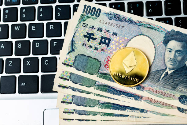 Ethereum coin and Japanese currency on laptop keyboard Fujian, China - May 30, 2018: Ethereum coin and Japanese currency on laptop keyboard. Ethereum is virtual currency.  With Ethereum  stock pictures, royalty-free photos & images