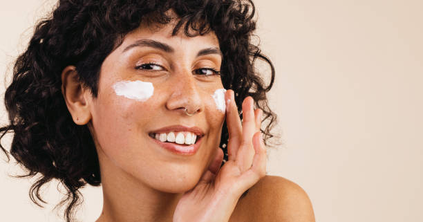 Ethnic woman moisturizing her face stock photo