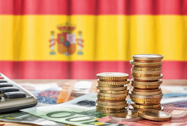Euro banknotes and coins in front of the national flag of Spain stock photo