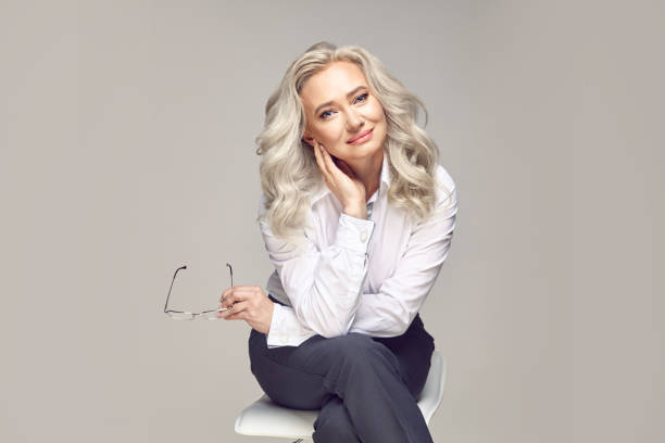 European middle aged female portrait, incredibly gentle senior mature woman dressed in strict business clothing looking at the camera with a adorable and smiling eyes on a grey isolated. Business portrait of a charming middle-aged woman with beautiful grey hair, dressed in a stylish casual look, posing in a studio on a gray isolated background with an empty space to copy. russian mature women stock pictures, royalty-free photos & images