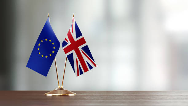 European Union And British Flag Pair On A Desk Over Defocused Background European Union and British flag pair on desk over defocused background. Horizontal composition with copy space and selective focus. brexit stock pictures, royalty-free photos & images