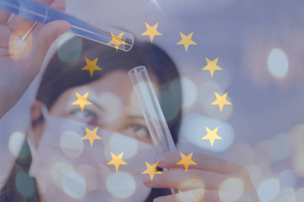 European union and cancer vaccine, young chemical female researcher holding syringe and ampoule with fluid in laboratory. stock photo