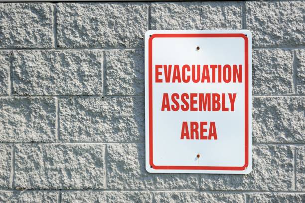 Evacuation assembly area sign Close up of evacuation assembly area sign on brick wall evacuation stock pictures, royalty-free photos & images