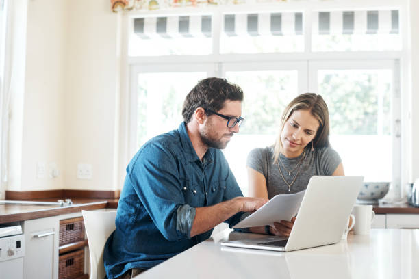 Evaluating their income and expenditure Shot of a young couple working on their finances together at home home insurance stock pictures, royalty-free photos & images