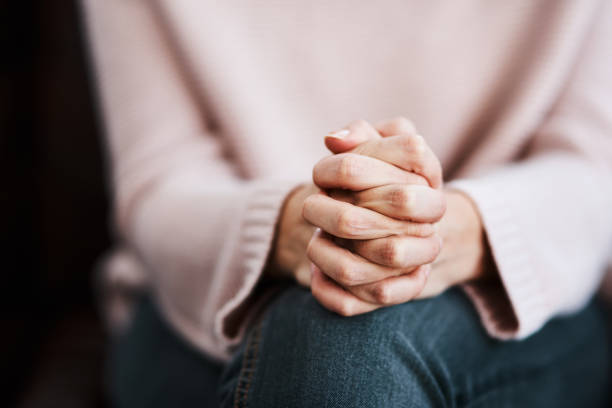 Even though it hurts, keep holding on Cropped shot of a woman sitting on a sofa and feeling anxious praying stock pictures, royalty-free photos & images
