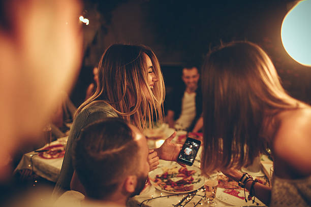 Evening with friends in a bistro Photo of a cheerful friends during the dinner party in an outdoors bistro, having fun while taking photos and selfies drinking photos stock pictures, royalty-free photos & images