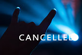Concert cancelled background. Word CANCELLED on photo with hand showing the gesture with two fingers up. Event cancelled concept. Festival cancelled background.
