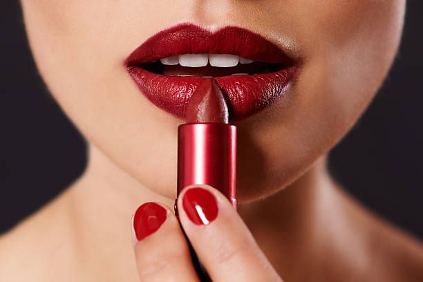 Every woman has a favourite shade... Closeup image of a woman applying lipstick painting fingernails stock pictures, royalty-free photos & images