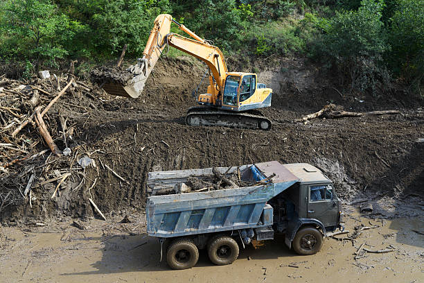 excavator clears  road from landslide stock photo