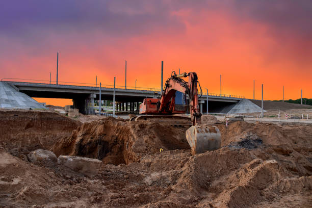 Excavator during excavation at construction site on amazing sunset background stock photo