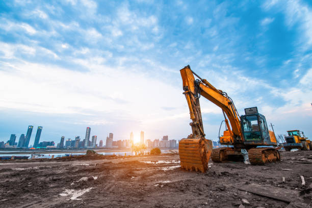 excavator in construction site on sunset sky background excavator in construction site on sunset sky background backhoe stock pictures, royalty-free photos & images