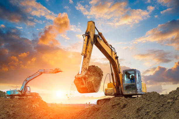 excavator in construction site on sunset sky excavator in construction site on sunset sky background agricultural machinery stock pictures, royalty-free photos & images