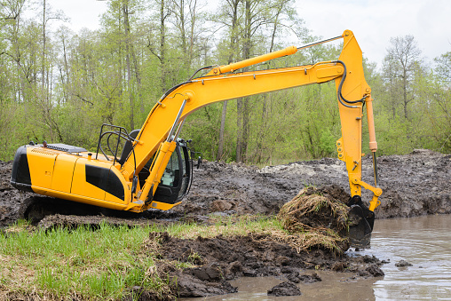 Excavator picks up big amount of soil for construction irrigation system canal in countryside for watering