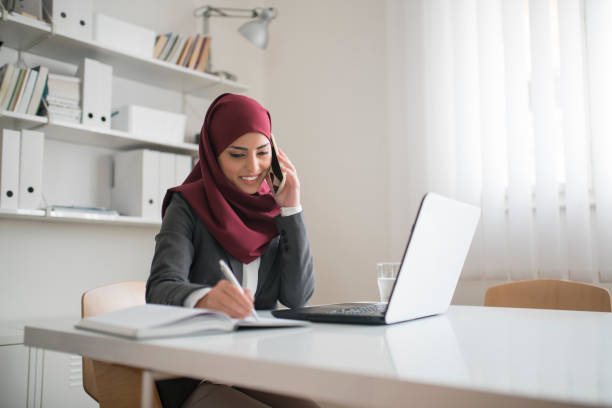 Excellent In Multitasking Muslim businesswoman working at her office. hijab stock pictures, royalty-free photos & images