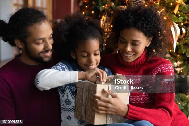 Excited African American family with kid open Christmas gifts