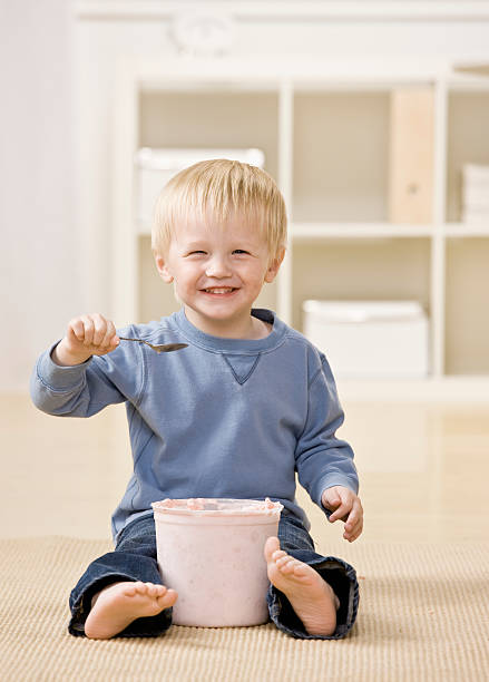 Excited boy eats ice cream from tub stock photo