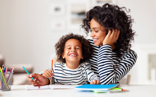excited ethnic mother and son doing homework - família monoparental imagens e fotografias de stock