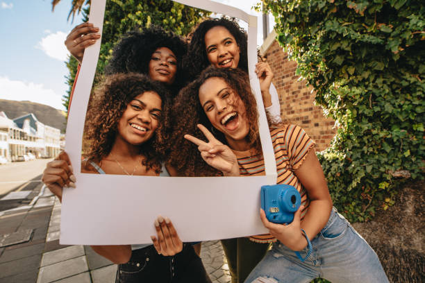 Excited friends with blank photo frame Excited female friends posing with blank photo frame. Smiling girls with empty picture frame outdoors in the city. female friendship photos stock pictures, royalty-free photos & images