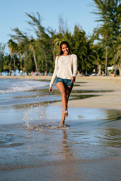 Excited girl at the beach Teenage girl wearing shorts and a sweater kicking up water while at the beach located in Luquillo, Puerto Rico. cute puerto rican girls stock pictures, royalty-free photos & images