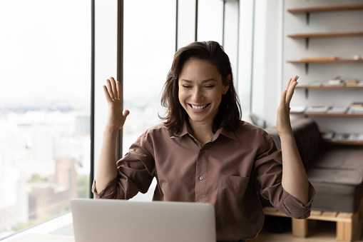 Excited happy business woman celebrating win, success, achieve, high result at laptop, getting job promotion, good news, reward, winning prize, looking at screen, making winner gesture