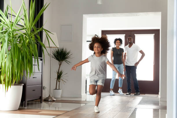 Excited little funny african girl running exploring big modern house on moving day Excited little funny african girl running exploring big modern house moving in, happy black parents and kid daughter coming into new home, cute mixed race child having fun in hallway, family mortgage returning home stock pictures, royalty-free photos & images