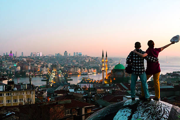 Excited Man and Woman staying rooftop overlooking city at sunrise stock photo