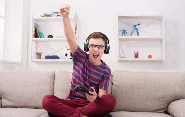 adolescente eccitato che gioca a videogiochi a casa - joystick soccer foto e immagini stock