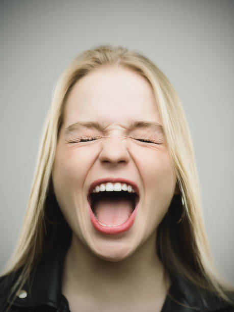 mujer emocionada gritando contra el fondo gris - boca abierta fotografías e imágenes de stock