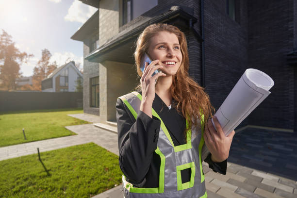 Excited woman site engineer with drawings talking on phone stock photo