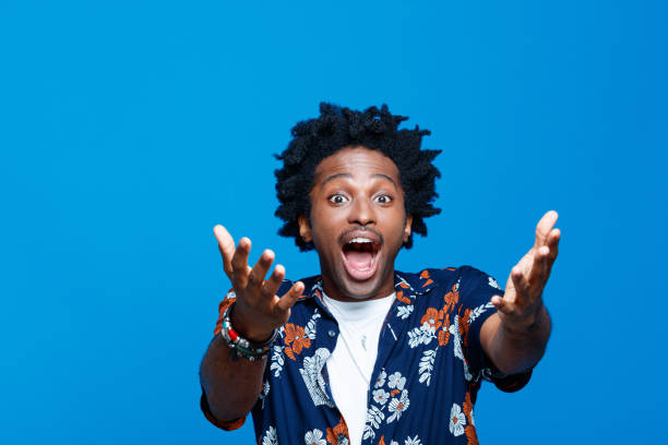 Excited young man in hawaiian shirt against blue background stock photo