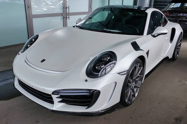 Exclusive white matte Porsche 911 turbo in exclusive wide and carbon body kit named Stinger from Topcar tuning. Parked on the street. Front left side  view stock photo