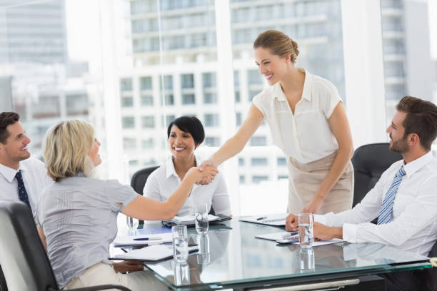 Side view of executives shaking hands during a business meeting in...