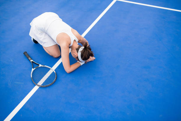 Exhausted Female Tennis Player High angle portrait of exhausted young woman sitting on floor in tennis court catching breath, copy space defeat stock pictures, royalty-free photos & images