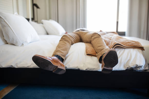 Exhausted from the business trip Businessman lying on hotel bed exhausted from the business trip. Tired man in formal clothes resting on hotel bed. worker returning home stock pictures, royalty-free photos & images