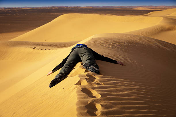exhausted-person-on-dune-in-libyan-desert-picture-id183378613