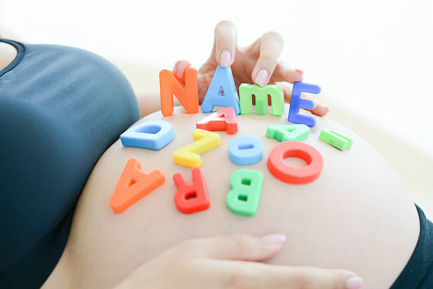 expectant mother spelling name on her pregnant belly stock photo