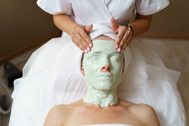 Experienced cosmetician removing alginate mask from a face of a caucasian woman. The process of removing the jellied alginate mask from the face of a woman. Facial rejuvenation procedure. Skin care in the beauty salon gelatin stock pictures, royalty-free photos & images