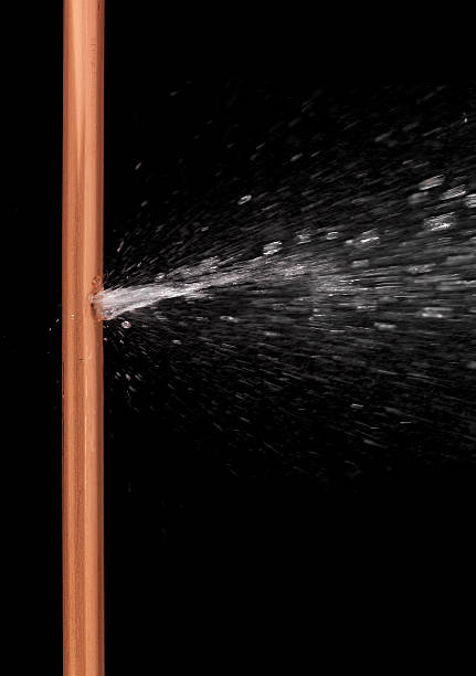 Exploding water pipe Copper pipe with water gushing from a hole Burst Pipe stock pictures, royalty-free photos & images
