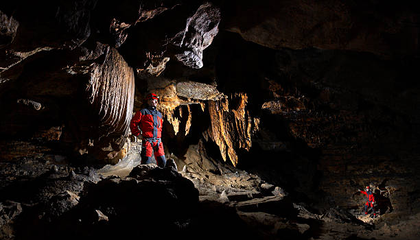 explorers venturing into hallow cave - speleologie buitensport stockfoto's en -beelden